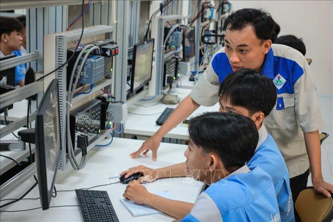 Kỹ sư Trần Hải Đăng - Giảng viên khoa Điện tử hướng dẫn sinh viên nghề Điện tử công nghiệp lập trình PLC. Ảnh: Hoàng Hiếu - TTXVN