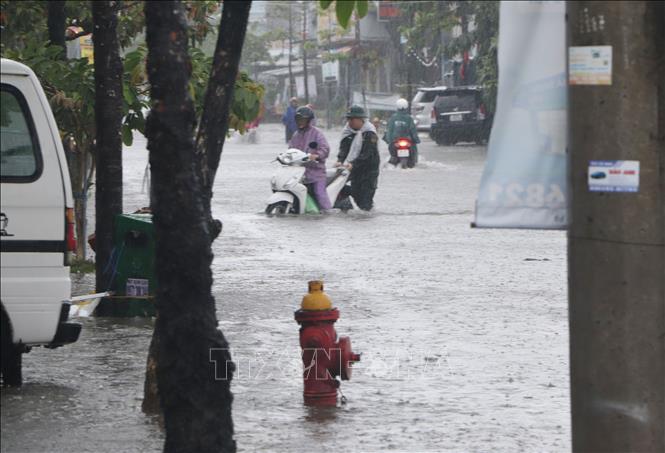 Bộ đội địa phương hỗ trợ người dân có xe gắn máy hư hỏng di chuyển qua đường ngập nước. Ảnh: Tuấn Phi - TTXVN