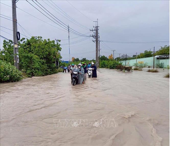 Nước ngập và tràn qua đoạn tuyến giao thông 709 (xã Thuận Nam) gây khó khăn cho lưu thông của người dân. Ảnh: TTXVN phát