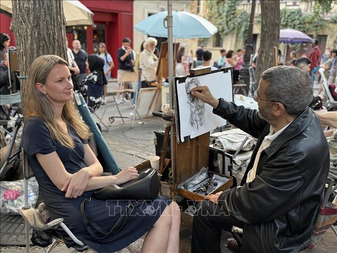 Một họa sĩ vẽ chân dung du khách tại Montmartre, nơi truyền thống hội họa đường phố vẫn được duy trì và trở thành nét đặc trưng thu hút du khách. Ảnh: Hữu Chiến - PV TTXVN tại Pháp