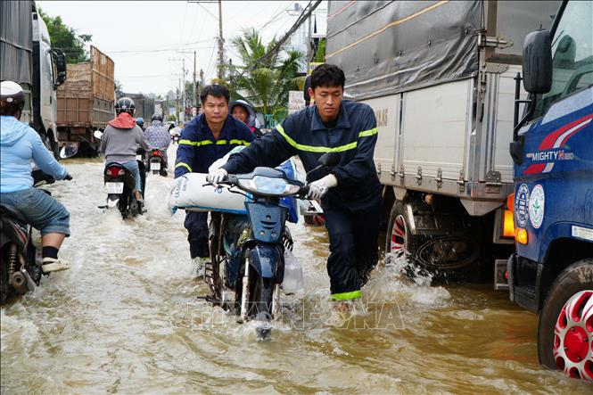 Xe chết máy, lực lượng chức năng hỗ trợ người dân xã Binh Minh, thành phố Đồng Nai di chuyển qua vùng nước ngập sâu. Ảnh: Lê Xuân - TTXVN