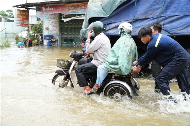 Người dân xã Binh Minh, thành phố Đồng Nai, được các chiến sĩ công an hỗ trợ di chuyển qua vùng nước ngập sâu. Ảnh: Lê Xuân - TTXVN