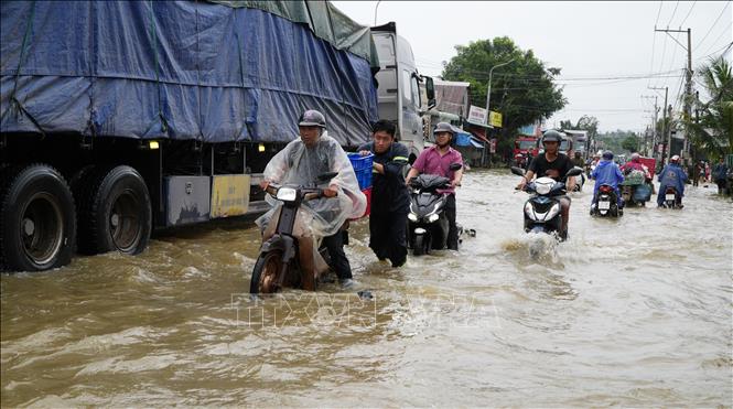 Người dân xã Binh Minh, thành phố Đồng Nai được các chiến sĩ công an hỗ trợ di chuyển qua vùng nước ngập sâu. Ảnh: Lê Xuân - TTXVN