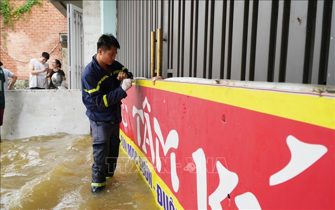 Cán bộ cảnh sát hỗ trợ nhà dân lắp tấm chắn nước tràn vào nhà tại ấp Sông Mây, xã Bình Minh, thành phố Đồng Nai. Ảnh: Lê Xuân - TTXVN