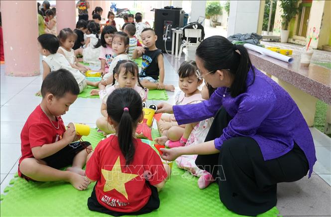 Cô giáo trường Mầm non Tây Nha Trang hướng dẫn học sinh làm đồ chơi lồng đèn Trung thu. Ảnh: Phan Sáu - TTXVN