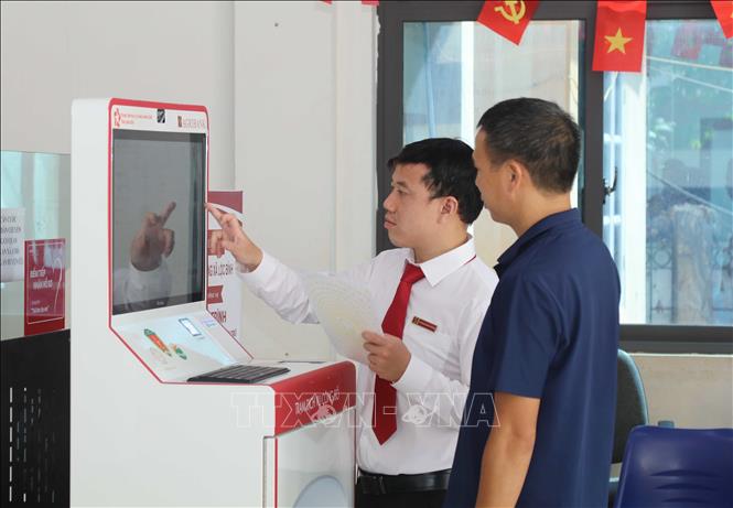 Cán bộ Agribank tỉnh Lạng Sơn hướng dẫn người dân thực hiện thủ tục hành chính qua “Trạm dịch vụ công số” xã Lộc Bình. Ảnh: Quang Duy – TTXVN