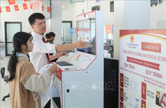 Cán bộ Agribank tỉnh Lạng Sơn hướng dẫn người dân thực hiện thủ tục hành chính qua “Trạm dịch vụ công số” xã Lộc Bình. Ảnh: Quang Duy – TTXVN