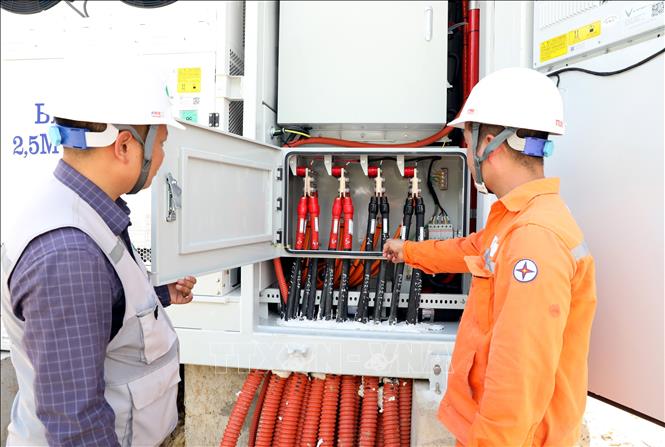 Đại diện các đơn vị liên quan kiểm tra các thiết bị thuộc hệ thống pin lưu trữ năng lượng trước khi đóng điện. Ảnh: Văn Đạt - TTXVN