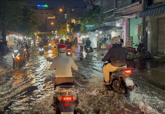 Các phương tiện lưu thông trên đường Trần Xuân Soạn, phường Tân Thuận, bị ngập do triều cường buổi tối 28/9. Ảnh: Hồng Đạt - TTXVN