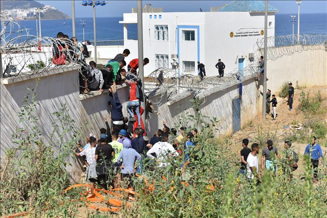 (Tư liệu) Người di cư trèo qua hàng rào biên giới để vào vùng lãnh thổ Ceuta của Tây Ban Nha từ thành phố Fnideq, Maroc. Ảnh: THX/TTXVN phát