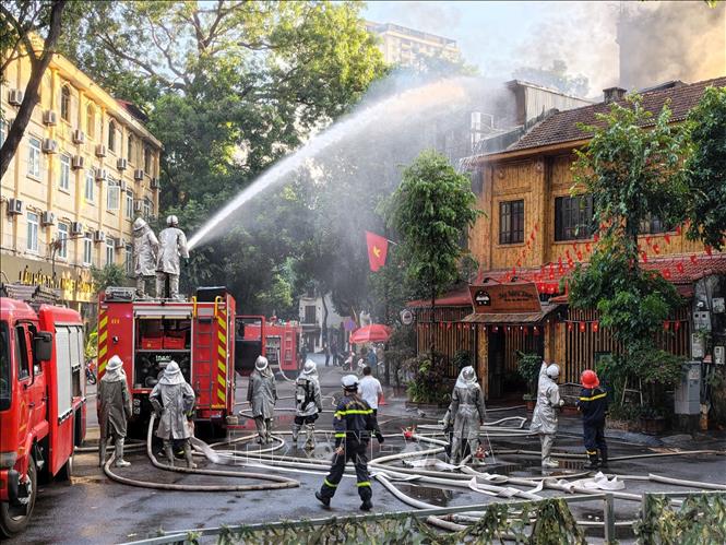 Lực lượng chức năng đang khẩn trương xử lý đám cháy. Ảnh: Lê Đông - TTXVN