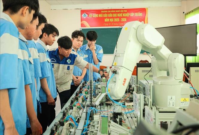 Thạc sĩ Nguyễn Tuấn Khanh – Giảng viên khoa Điện tử hướng dẫn sinh viên tìm hiểu thành phần các trạm điều khiển trong dây chuyền sản xuất linh hoạt, hiện đại, gắn với hoạt động điều khiển robot. Ảnh: Hoàng Hiếu – TTXVN