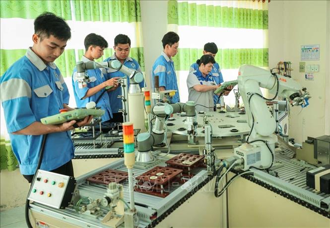 Thạc sĩ Phan Hoài Loan – giảng viên khoa Điện tử đang hướng dẫn sinh viên nghề Cơ điện tử vận hành cánh tay Robot, qua đó giúp sinh viên hiểu và gắn lý thuyết với thực hành và ứng dụng công nghệ vào nghiên cứu, sáng tạo robot. Ảnh: Hoàng Hiếu – TTXVN