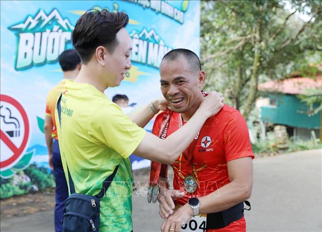 Ban tổ chức trao huy chương hoàn thành về đích cự ly 5km cho các VĐV. Ảnh: Quý Trung - TTXVN