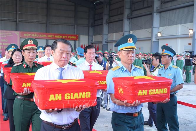 Lãnh đạo các địa phương đưa mẫu sinh phẩm hài cốt liệt sĩ lên máy bay. Ảnh: Hữu Tài/TTXVN phát