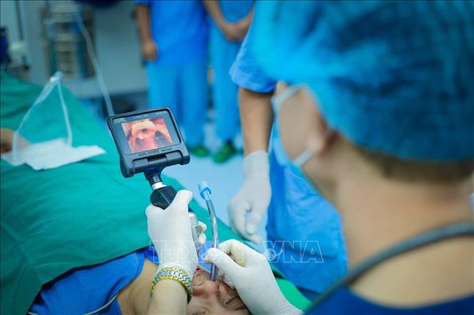 PGS.TS, Thầy thuốc Nhân dân Nguyễn Quang Bình quan sát hình ảnh đường thở trên màn hình thiết bị hỗ trợ trong quá trình đặt nội khí quản cho người bệnh. Ảnh: Phạm Tuấn Anh - TTXVN