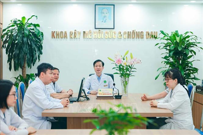 PGS.TS Nguyễn Quang Bình chủ trì buổi trao đổi công việc với đội ngũ nhân viên Khoa Gây mê hồi sức và Chống đau. Trên cương vị trưởng khoa, ông cùng đồng nghiệp thực hiện nhiệm vụ chuyên môn, gắn công tác điều trị với đào tạo và phát triển đội ngũ. Ảnh: Phạm Tuấn Anh - TTXVN