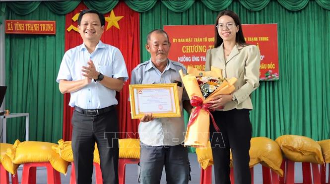Lãnh đạo xã Vĩnh Thạnh Trung  trao thư cảm ơn nhà tài trợ đã hỗ trợ 6 tấn gạo cho các hộ nghèo, hộ cận nghèo trên địa bàn. Ảnh: Thanh Sang – TTXVN