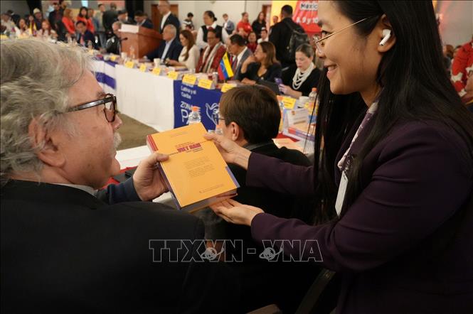 Tặng cuốn sách “Khát vọng Việt Nam hùng cường trong kỷ nguyên mới’’ cho các trưởng đoàn tham dự hội thảo. Ảnh: Phi Hùng - PV TTXVN tại Mexico
