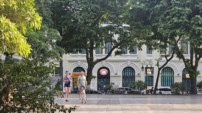 Du khách quốc tế dạo bước dưới những tán cây xanh bên hồ Hoàn Kiếm, tận hưởng không khí dịu mát của Thủ đô. Ảnh: Tuyết Mai – TTXVN