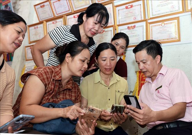  Cán bộ ngân hàng Chính sách Xã hội tỉnh Lào Cai hướng dẫn Tổ trưởng tổ tiết kiệm và vay vốn (TK&VV) sử dụng phần mềm trên điện thoại. Ảnh: Trần Việt - TTXVN