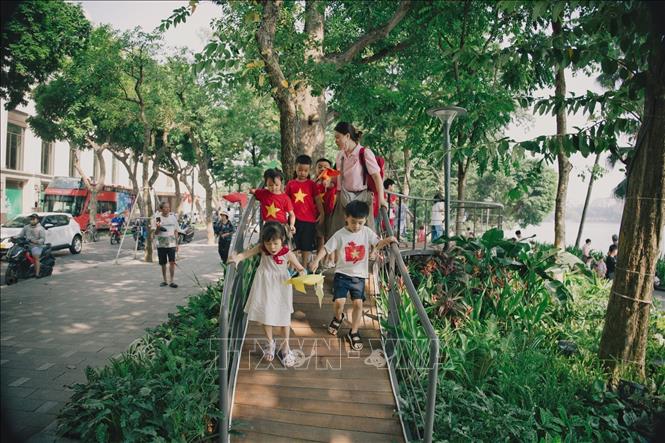 Các em nhỏ cùng cô giáo vui chơi trên cầu cảnh quan thuộc không gian nghệ thuật “Dải lụa ký ức” bên hồ Hoàn Kiếm. Ảnh: Phạm Tuấn Anh - TTXVN