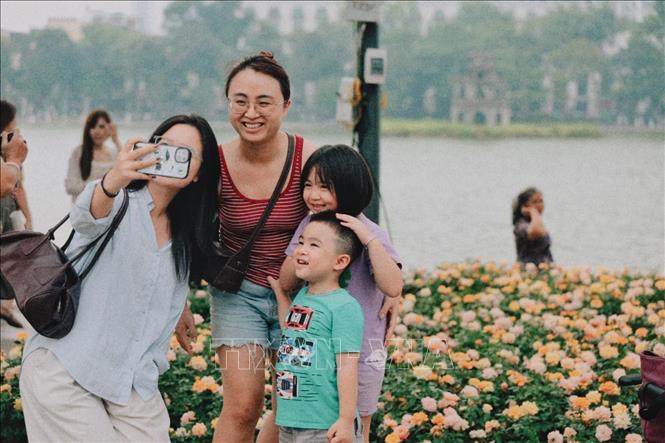 Người dân hào hứng chụp ảnh lưu niệm bên những vườn hoa rực rỡ sắc màu tại khu vực hồ Hoàn Kiếm. Ảnh: Phạm Tuấn Anh - TTXVN