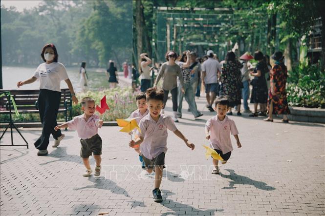 Các em nhỏ vui đùa với chong chóng. Ảnh: Phạm Tuấn Anh - TTXVN