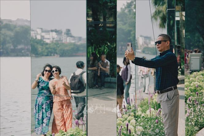 Người dân thích thú chụp ảnh lưu niệm bên hệ thống gương phản chiếu tại không gian nghệ thuật “Dải lụa ký ức” ven hồ Hoàn Kiếm, một điểm tham quan mới trong dịp kỷ niệm 72 năm Ngày Giải phóng Thủ đô. Ảnh: Phạm Tuấn Anh - TTXVN