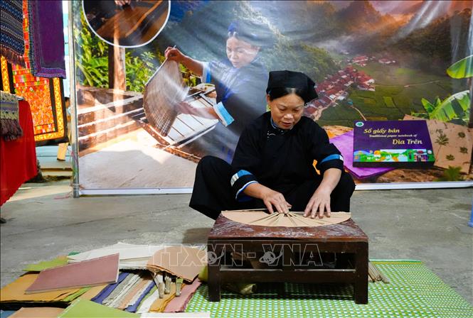 Chị Nông Thị Kính, xóm Rìa Trên, xã Quảng Uyên đang làm sản phẩm quạt bằng giấy bản truyền thống. Ảnh: Chu Hiệu-TTXVN.