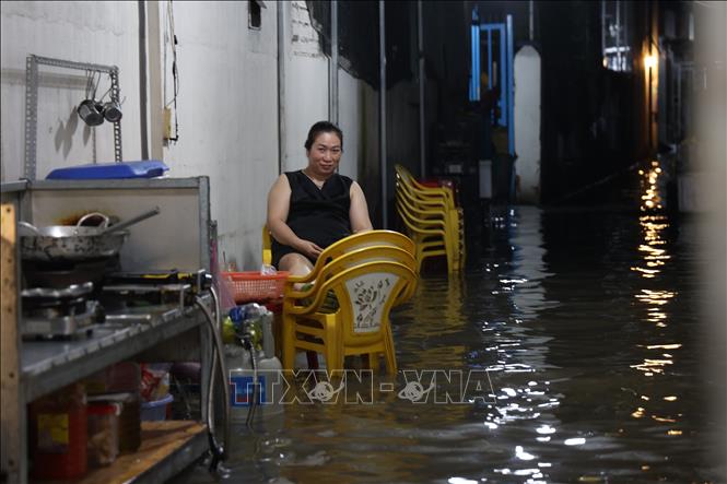 Chị Nguyễn Thị Cẩm Ly chờ khách trong cảnh ngập nước. Ảnh: Hồng Đạt - TTXVN