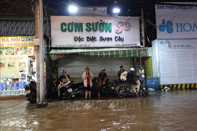 Nhiều người dân phải ngừng di chuyển, chờ đợi nước rút dần trên đường Phạm Hữu Lầu, phường Tân Mỹ, ngập sâu do triều cường tối 11/10. Ảnh: Hồng Đạt - TTXVN