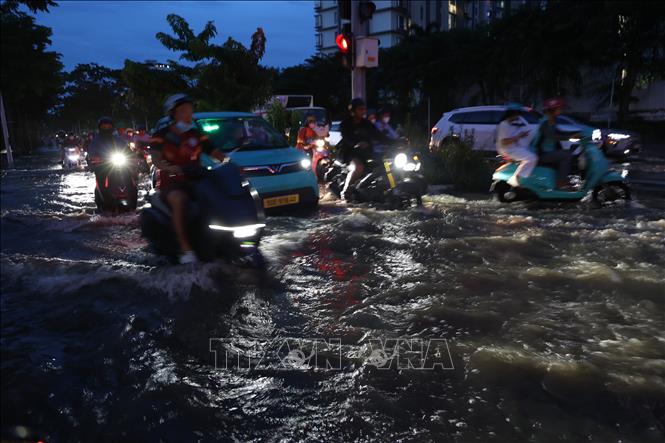 Các phương tiện di chuyển qua khu vực ngã tư Nguyễn Lương Bằng - Hoàng Quốc Việt, bị ảnh hưởng nặng do triều cường tối 11/10. Ảnh: Hồng Đạt - TTXVN