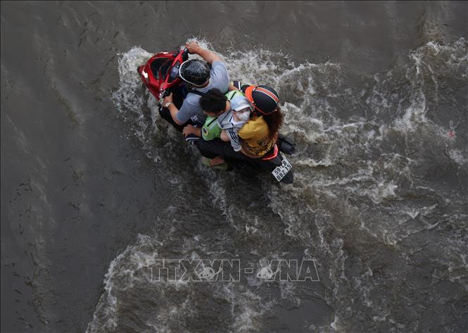 Các phương tiện lưu thông trên đường Trần Xuân Soạn, phường Tân Thuận, bị ngập do triều cường chiều 11/10. Ảnh: Hồng Đạt - TTXVN