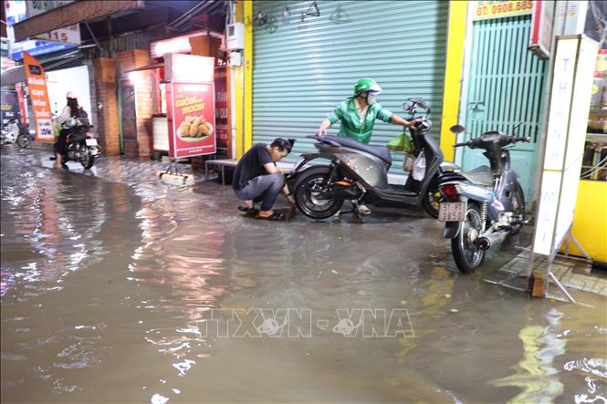 Sửa xe trên vỉa hè đường Phạm Hữu Lầu, phường Tân Mỹ, thời điểm triều cường làm đường ngập sâu tối ngày 11/10. Ảnh: Hồng Đạt - TTXVN