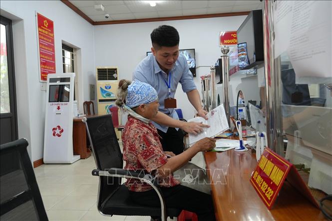 Ông Phạm Quang Huy, Phó Giám đốc Trung tâm Phục vụ hành chính công xã Yên Mỹ (Hưng Yên) hướng dẫn người dân kê khai, nộp hồ sơ. Ảnh: Mạnh Khánh - TTXVN