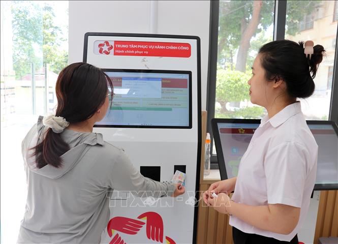 Tư vấn viên của Trung tâm Phục vụ hành chính công phường Cam Ranh hướng dẫn người dân dùng VneID tra cứu thông tin từ robot AL để hỗ trợ các thủ tục hành chính. Ảnh: Công Thử - TTXVN