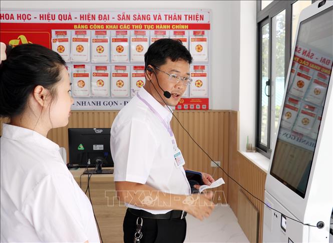 Lãnh đạo Trung tâm Phục vụ hành chính công phường Cam Ranh hướng dẫn nhân viên tư vấn sử dụng công nghệ hỗ trợ giải quyết thủ tục hành chính cho người dân.  Ảnh: Công Thử - TTXVN