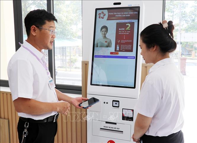 Lãnh đạo Trung tâm Phục vụ hành chính công phường Cam Ranh hướng dẫn nhân viên tư vấn sử dụng công nghệ hỗ trợ giải quyết thủ tục hành chính cho người dân. Ảnh: Công Thử - TTXVN