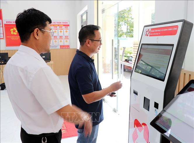 Lãnh đạo Trung tâm Phục vụ hành chính công phường Cam Ranh hướng dẫn người dân sử dụng robot Al để tra cứu các thủ tục hành chính. Ảnh: Công Thử - TTXVN