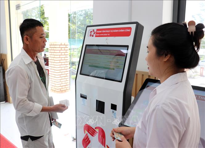 Tư vấn viên của Trung tâm Phục vụ hành chính công phường Cam Ranh hướng dẫn người dân dùng VneID tra cứu thông tin từ robot AL để hỗ trợ các thủ tục hành chính. Ảnh: Công Thử - TTXVN