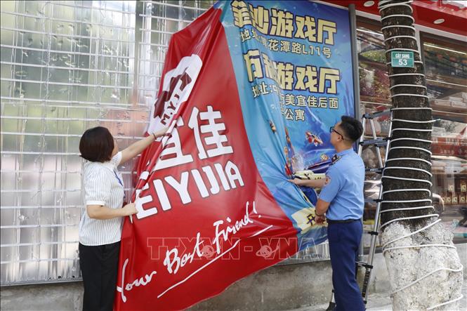 Lực lượng chức năng yêu cầu các cơ sở gỡ bỏ các biển hiệu chưa phù hợp tại phường Kinh Bắc, thành phố Bắc Ninh. Ảnh: Thái Hùng - TTXVN