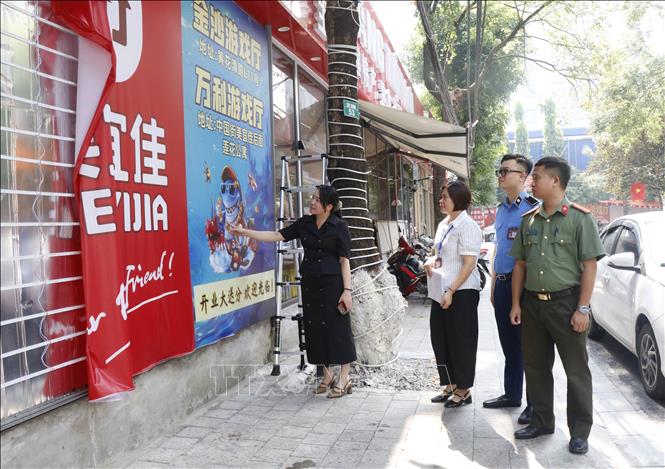 Bà Nguyễn Thị Hiền, Phó Chủ tịch UBND phường Kinh Bắc (ngoài cùng bên trái) kiểm tra và yêu cầu tháo dỡ những biển hiệu chưa phù hợp. Ảnh: Thái Hùng - TTXVN