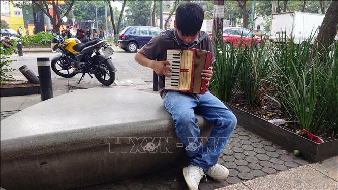 Một thanh niên biểu diễn đàn để mưu sinh tại thủ đô Mexico City, Mexico. Ảnh: Phi Hùng - PV TTXVN tại Mỹ Latinh