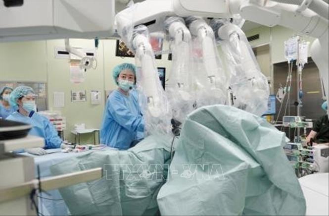 Bác sĩ thực hiện ca phẫu thuật tại Bệnh viện trực thuộc Đại học Hirosaki, tỉnh Aomori, Nhật Bản với sự tham gia của bác sĩ điều khiển robot từ xa. Ảnh: Ảnh: Kyodo/TTXVN phát