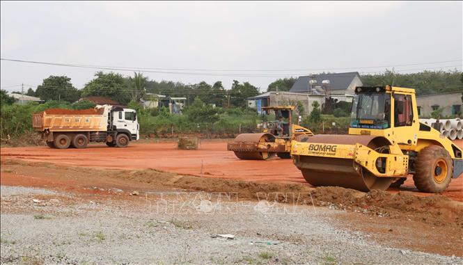 Xe ben vận chuyển đất, phối hợp với máy lu thi công nền đường tại phường Đồng Phú, thành phố Đồng Nai. Ảnh: Đậu Tất Thành - TTXVN