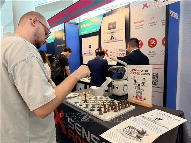 Khách tham quan triển lãm thử nghiệm chơi cờ với robot. Ảnh: Lê Anh - PV TTXVN tại Hong Kong (Trung Quốc)