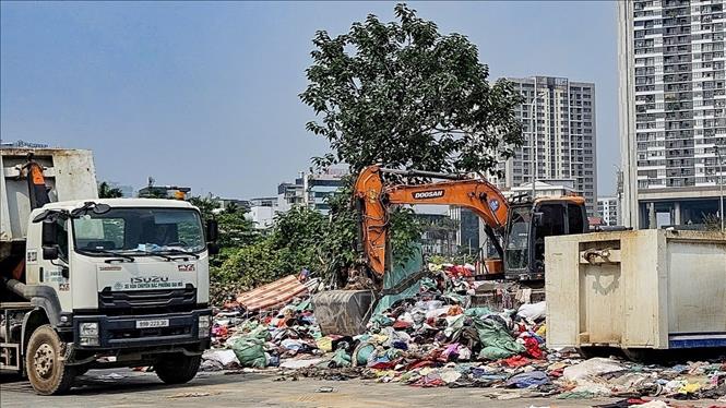 Lực lượng vệ sinh môi trường huy động phương tiện cơ giới thu gom lượng lớn quần áo cũ tồn đọng tại phường Từ Liêm (Hà Nội). Ảnh: Trung Nguyên - TTXVN.