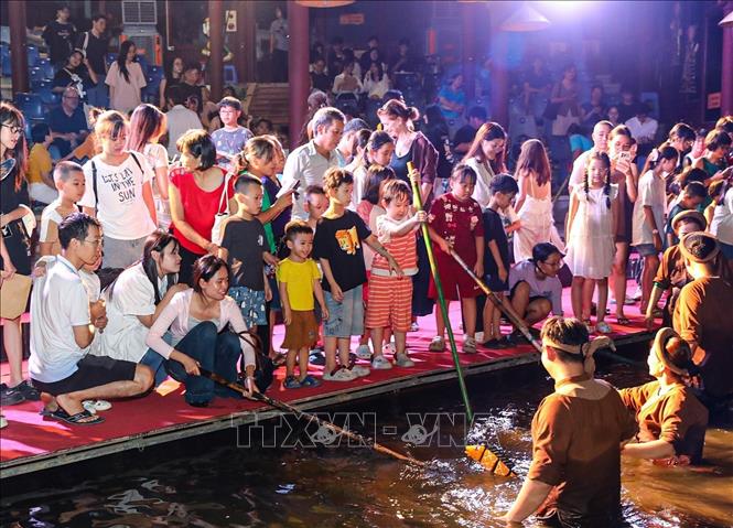 Khán giả trải nghiệm trực tiếp điều khiển con rối dưới sự hướng dẫn của các nghệ nhân múa rối nước. Ảnh: Khánh Hoà - TTXVN