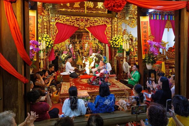 Toàn cảnh không gian thực hành nghi lễ hầu đồng tại đình Đông Thành, với thanh đồng thực hiện các động tác diễn xướng trước ban thờ, bên cạnh những người phụ lễ và đông đảo người dân tham dự. Ảnh: Phạm Tuấn Anh - TTXVN